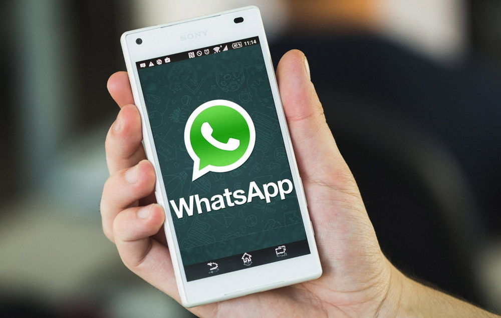 Белый телефон в руке с WhatsApp